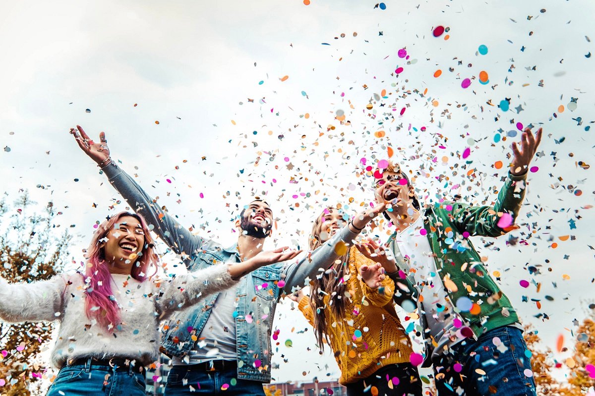 Four people throwing confetti in the air