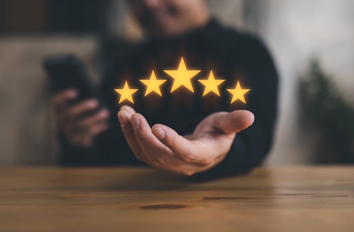 A customer's hand holding a five-star rating.