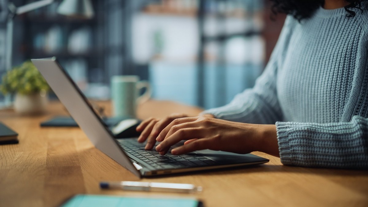 Woman sitting at a table while typing on her laptop.