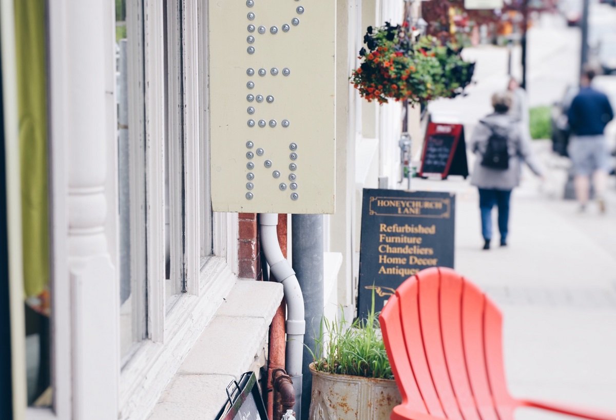 A vertical open sign outside a small business with a red chair under it.