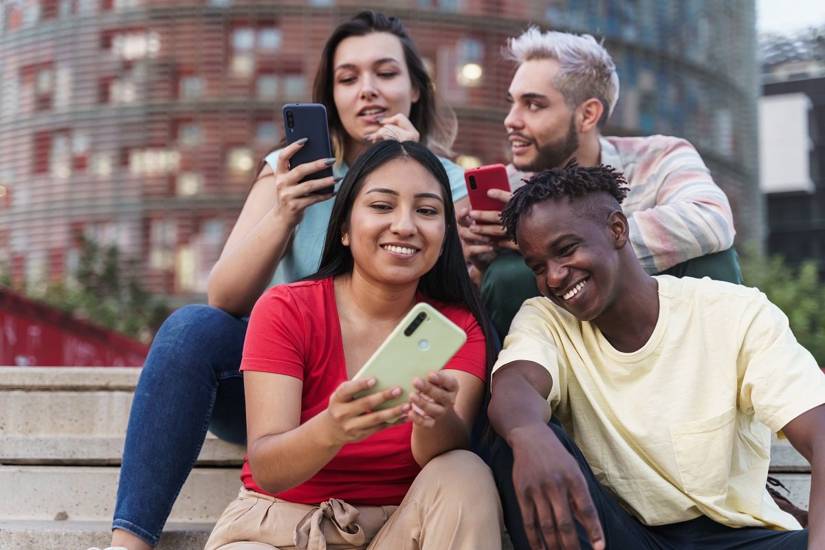 Four young adults looking at social media on their phones.