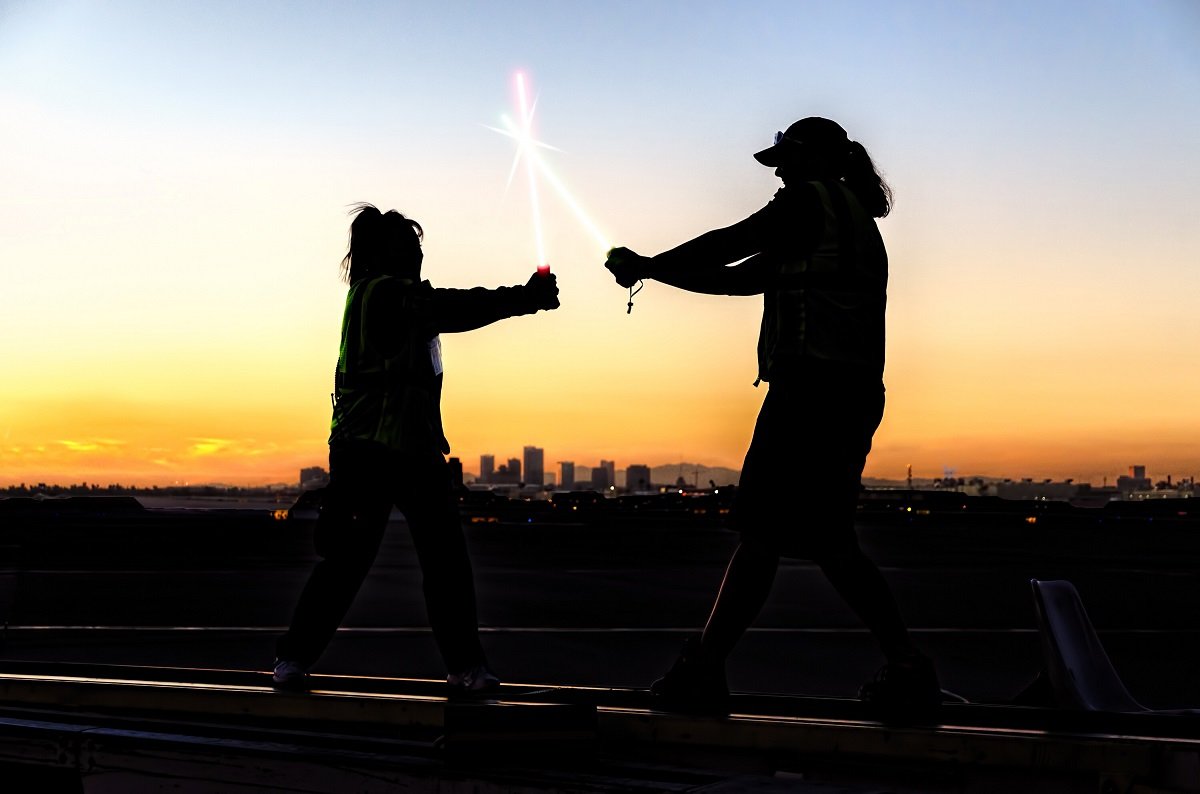 Two people dueling with lightsabers in the dark with a city in the background.